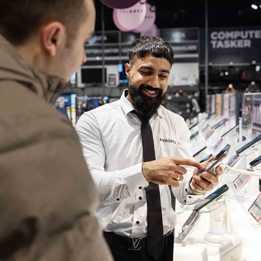 Employee from Power in Frederiksberg shows a customer a mobile phone.